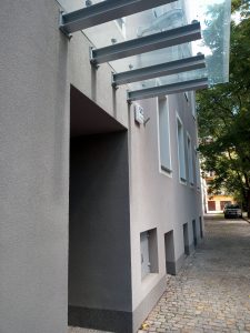 Zdjęcie pod kątem ukazujące budynek z wlotem na drzwi oraz zadaszeniem