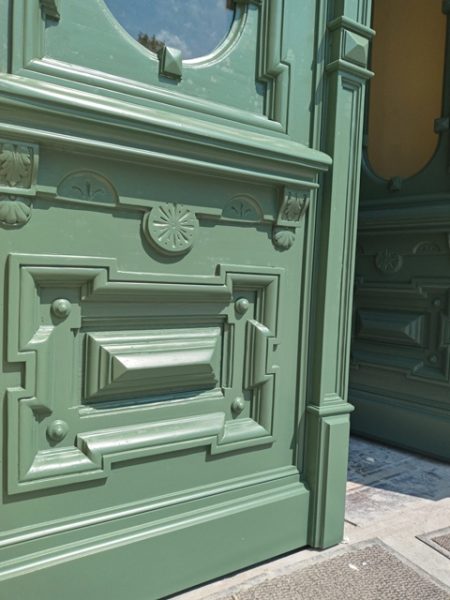 Fragment drzwi w kolorze zielonym z widocznymi zdobieniami
