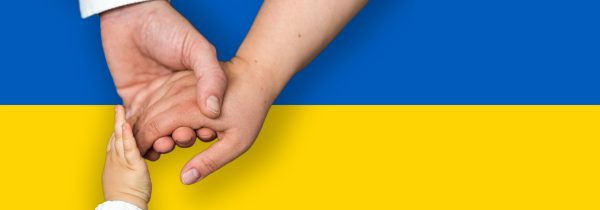 Grafika z flagą Ukrainy (poziome pasy niebieski i żółty) a na niej złączone trzy dłonie osób w różnym wieku