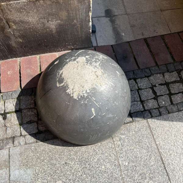 Zniszczona dekoracyjna kula na chodniku dodatkowo porysowana