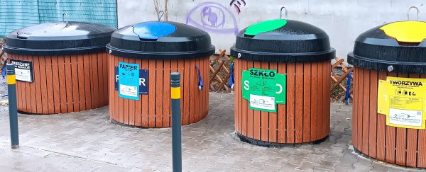 Widok na specjalne pojemniki na śmieci wmontowane to połowy w ziemie; zaznaczona kolorystyka recyklngu
