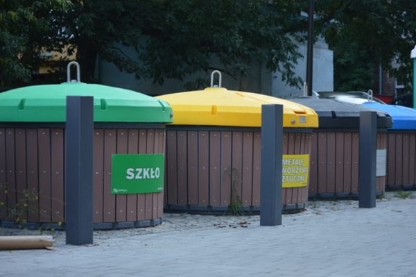 Widok na specjalne pojemniki na śmieci wmontowane to połowy w ziemie; zaznaczona kolorystyka recyklngu