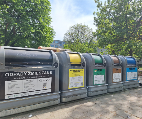 Widok na systemowe pojemniki na śmieci; szare pojemniki z widocznymi frakcjami