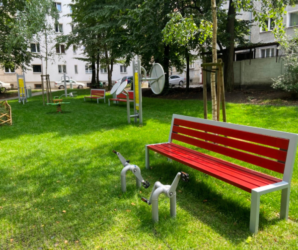 Na zdjęciu widoczna jest postawiona na trawniku ławeczka