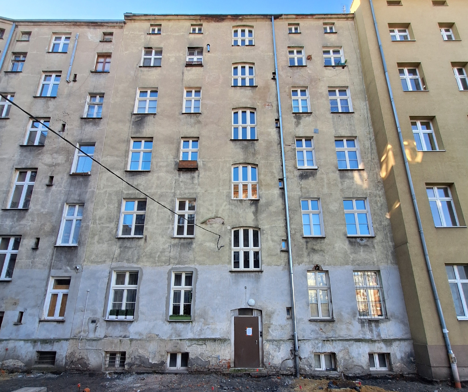 Widok na gładką miejską elewację kamienicy widzianą od podwórza
