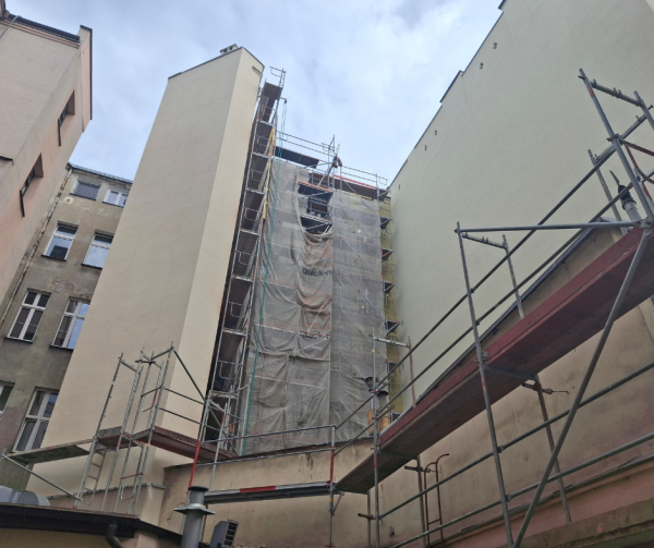 Widok na elewacje od podwórza, część jest wyremontowana z nowym tynkiem, fragment jest z rusztowaniem